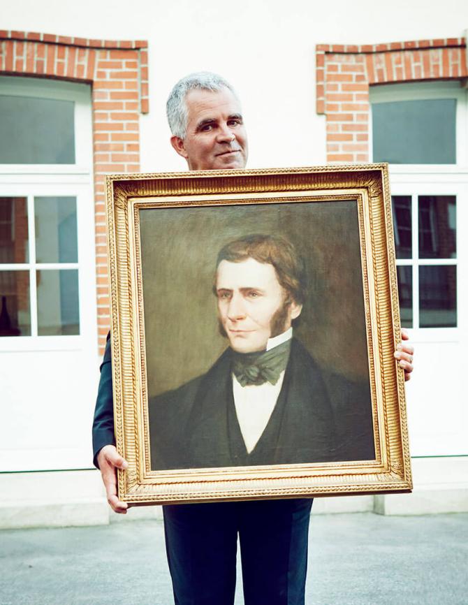 Olivier Krug holding a portrait of Maison Krug founder Joseph Krug